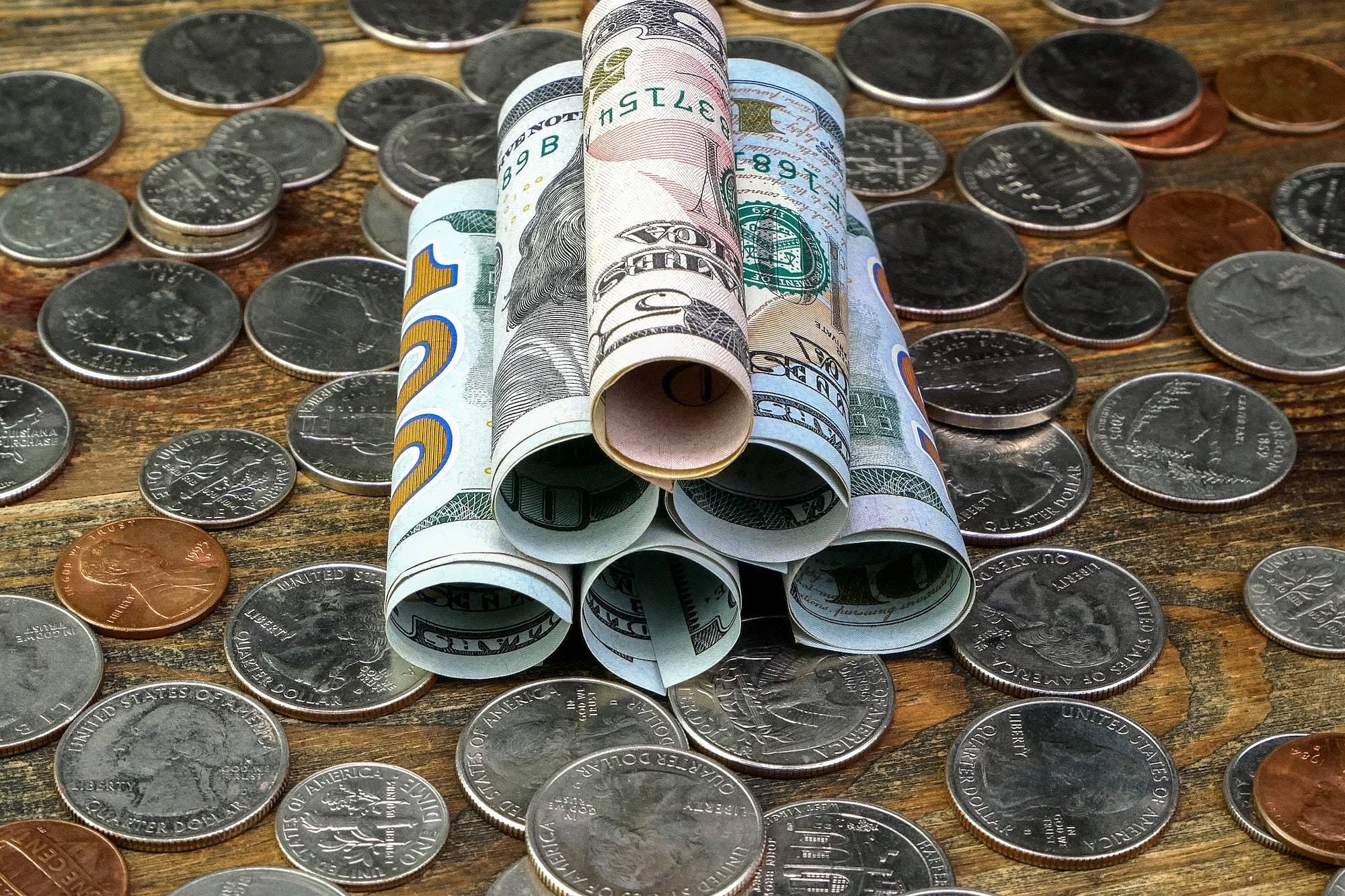 American dollars banknotes rolled into tube and us coins. Cash and saving of financial assets.